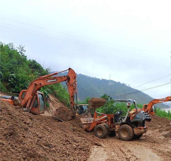 Xúc dọn đất đá sạt lở trên quốc lộ 14B, đoạn qua địa phận xã Bến Giằng. Ảnh: CÔNG TÚ