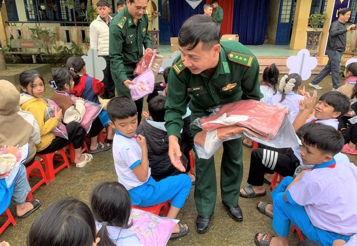 Thượng tá Trịnh Văn Kiên, Đồn trưởng Đồn Biên phòng Đắc Pring (hàng trước) trao áo ấm cho học sinh địa phương. Ảnh: TRỊNH TÙNG