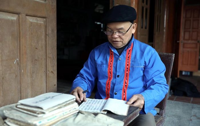 Nghệ nhân Nhân dân Sầm Văn Dừn nghiên cứu các cuốn cổ của đồng bào dân tộc Cao Lan. Ảnh: Quang Cường – TTXVN