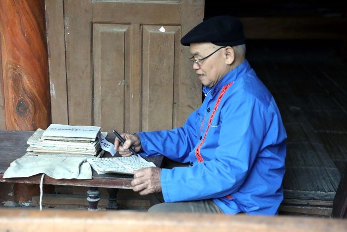 Nghệ nhân Nhân dân Sầm Văn Dừn nghiên cứu các cuốn cổ của đồng bào dân tộc Cao Lan. Ảnh: Quang Cường – TTXVN