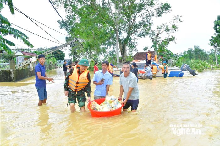 Cán bộ, chiến sĩ Bộ Chỉ huy Quân sự tỉnh Nghệ An và cấp ủy, chính quyền địa phương tiếp tế lương thực thực phẩm và nước uống cho bà con Nhân dân bị cô lập tại thôn Xuân Hương, xã Tân An. Ảnh: Trọng Kiên