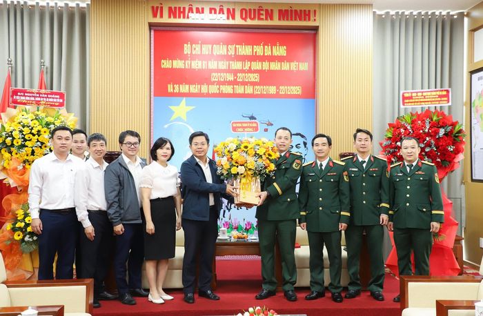 Lãnh đạo Văn phòng Thành ủy (bên trái) tặng hoa chúc mừng Bộ Chỉ huy Quân sự thành phố. Ảnh: NGỌC PHÚ
