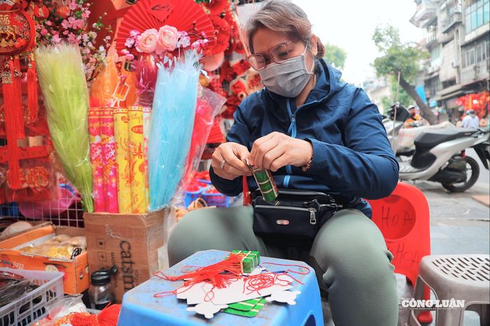 Các tiểu thương tranh thủ sáng sớm làm thủ công những món đồ trang trí như bánh chưng, bánh tét... để bày bán phục vụ người dân mua sắm.