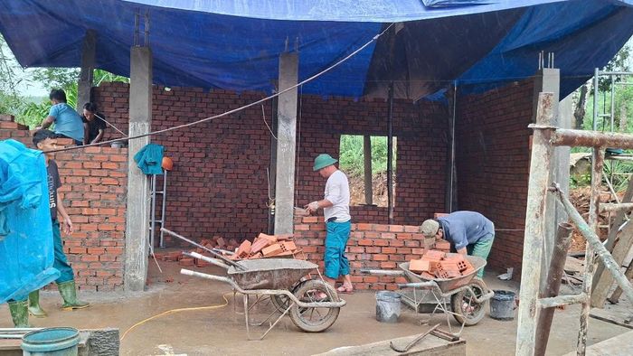 Lực lượng dân quân thường trực xã Hiệp Đức cùng hỗ trợ ngày công trong quá trình xây nhà. Ảnh: HỒNG BỘ