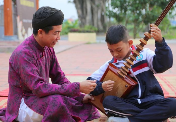 Nghệ nhân Ưu tú Tô Văn Tuyên, Chủ nhiệm Câu lạc bộ ca trù Đông Môn, hướng dẫn học sinh Trường Tiểu học Hòa Bình chơi đàn đáy. Ảnh: Minh Thu - TTXVN