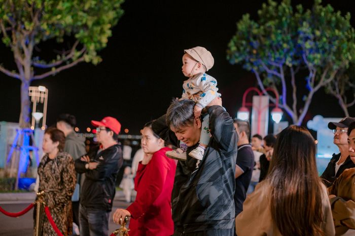 Một em bé được người thân đưa đi xem các hoạt động văn hóa - giải trí trong tiết trời se lạnh về đêm.