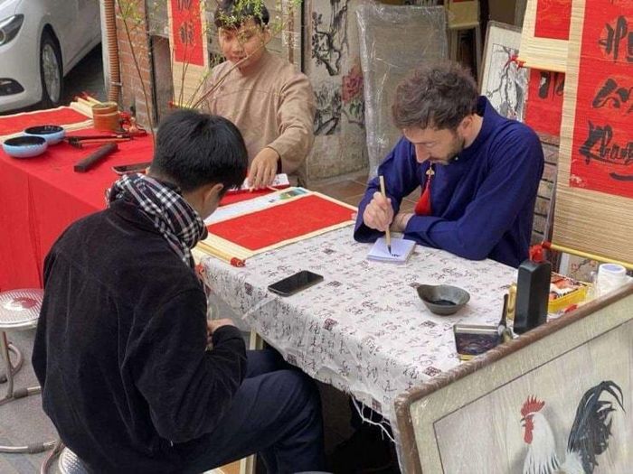 Du khách học viết chữ Nho tại Văn Miếu Quốc Tử Giám.