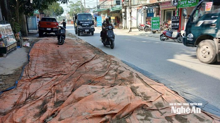 Do bùn đất và bụi bặm kéo dài, nhiều hộ dân đã phải căng bạt che chắn tạm giữa đường để hạn chế ảnh hưởng đến sinh hoạt. Ảnh: Đình Tuyên