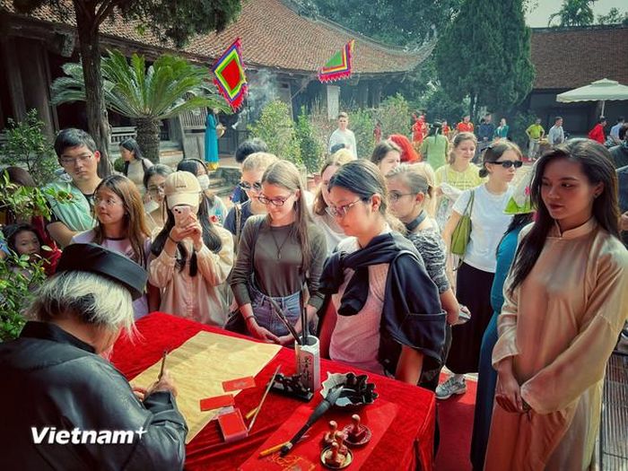  Du khách tìm hiểu phong tục xin chữ đầu Xuân ở Việt Nam. (Ảnh: Mai Mai/Vietnam+) 