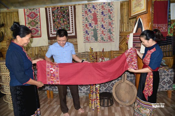 Bà Sầm Thị Bích (ngoài cùng bên trái) giới thiệu với khách du lịch sản phẩm khăn quàng thổ cẩm được dệt thủ công từ tơ tằm của HTX làng nghề Hoa Tiến. Ảnh: Hoài Thu
