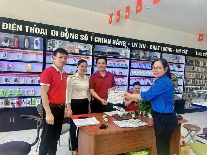Hộ kinh doanh tiếp nhận tờ rơi giới thiệu về ứng dụng thuế điện tử của ngành Thuế. Ảnh: TN