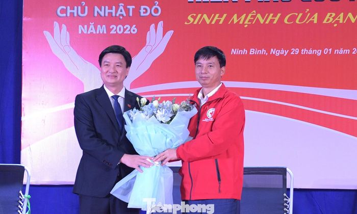 Ông Tống Văn Tam – Chủ tịch Hội Chữ thập đỏ tỉnh Ninh Bình tặng hoa anh Trần Ngọc Nam - Bí thư Tỉnh Đoàn Ninh Bình. Ảnh: Xuân Tùng