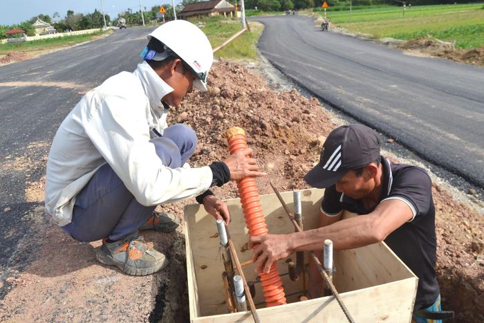 Công nhân chuẩn bị đúc đế trụ điện chiếu sáng đường dẫn phía đông. Ảnh: CÔNG TÚ