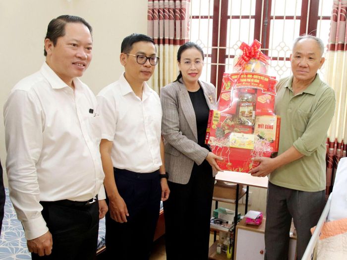 Phó Chủ tịch UBND thành phố Nguyễn Thị Anh Thi (thứ 3, bên trái sang) trao quà Tết cho thân nhân cụ bà Nguyễn Thị Phương. Ảnh: TRỌNG HUY