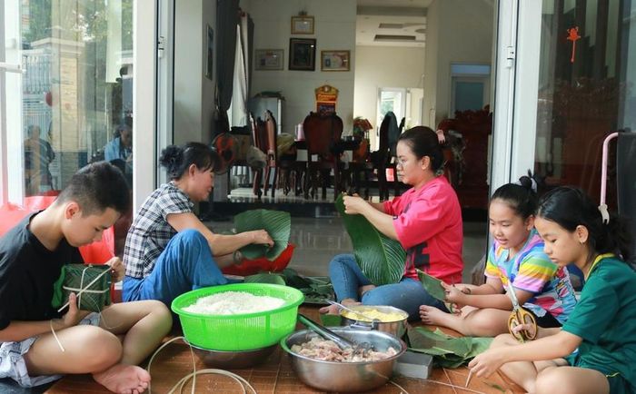 Người lớn hướng dẫn trẻ nhỏ gói bánh chưng là cách gìn giữ phong tục Tết bằng những trải nghiệm trực tiếp. Ảnh minh họa: INT.