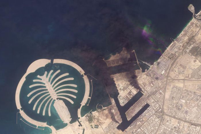  Khi không phận UAE tạm thời đóng cửa, một số cư dân đã lái xe đến những khu vực yên tĩnh hơn trong nước. Tại Hatta, gần biên giới Oman, một khách sạn đã chuyển phòng hội nghị thành nơi trú tạm cho các du khách đã trả phòng nhưng chưa thể rời đi vì chuyến bay bị gián đoạn. Một số khách mới đến cho biết họ đưa gia đình rời khỏi những khu vực ở Dubai từng ghi nhận các vụ tấn công. Ảnh vệ tinh chụp cảng Jebel Ali tại Dubai ngày 1/3 cho thấy một bến neo tàu bị cháy sau khi mảnh vỡ từ một tên lửa bị đánh chặn rơi xuống khu vực này. Ảnh: Planet Labs PBC. 