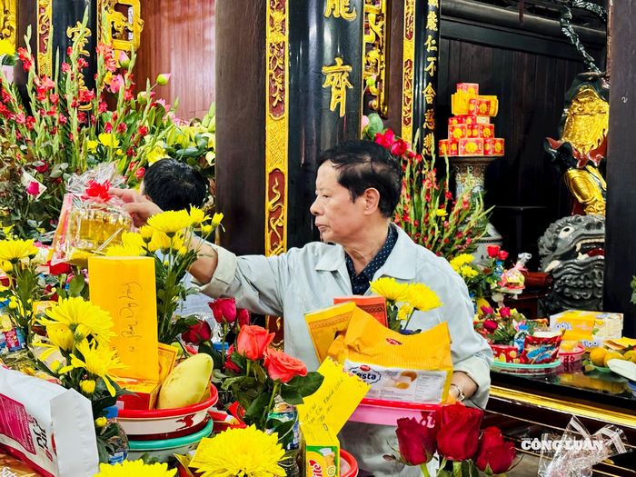 Ông Hòa đang kính cẩn sắp mâm lễ lên ban thờ Tam Bảo.