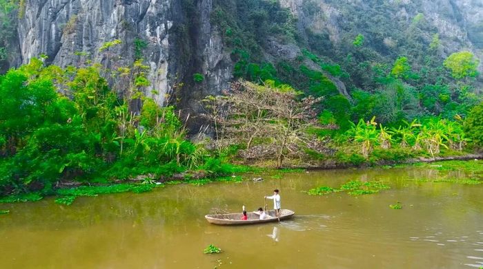 Ông Nguyễn Huy Phương chèo đò đưa khách tham quan chữ Thần trên vách núi