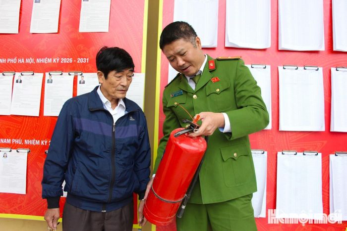 Thiếu tá Nguyễn Đăng Tuấn hướng dẫn thành viên tổ bầu cử số 15 xã Nam Phù sử dụng bình chữa cháy. Ảnh: MH