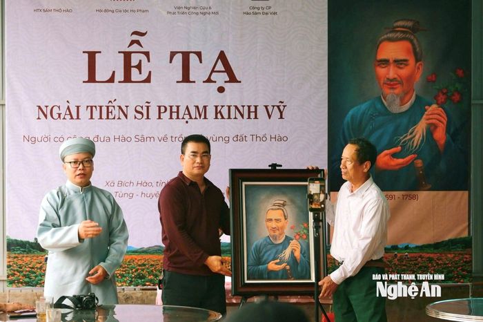 Họa sĩ Nguyễn Tô Cảnh trao bức chân dung Tiến sĩ Phạm Kinh Vỹ cho đại diện dòng họ Phạm ở xã Bích Hào. Ảnh: Võ Khánh