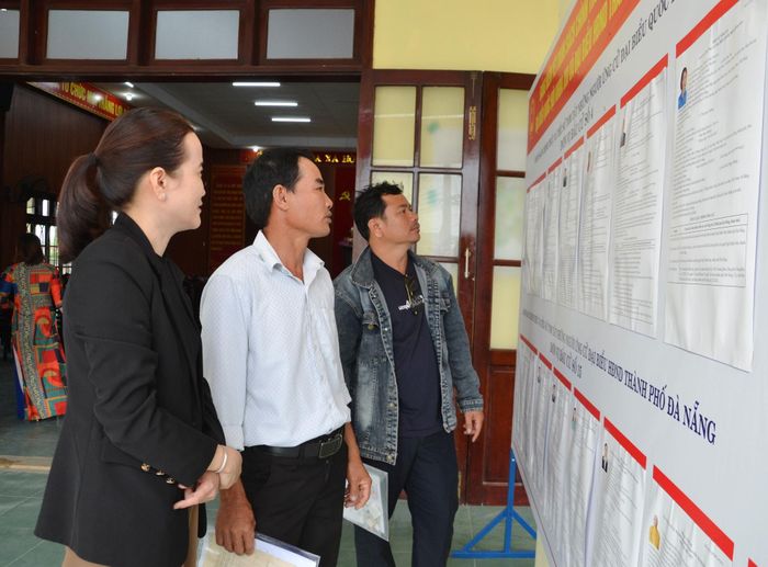 Cử tri xem lý lịch trích ngang của các ứng cử viên được công khai tại trụ sở HĐND, UBND xã Thăng Điền. Ảnh: CÔNG TÚ