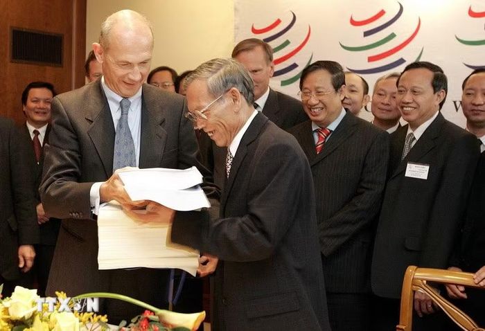 Trước sự chứng kiến của Phó Thủ tướng Phạm Gia Khiêm, Tổng Giám đốc WTO Pascal Lamy trao các văn kiện về việc kết nạp Việt Nam trở thành thành viên chính thức thứ 150 của WTO cho Bộ trưởng Thương mại Việt Nam Trương Đình Tuyển, tại buổi lễ kết nạp Việt Nam vào WTO, ngày 7/11/2006, tại trụ sở WTO ở Geneva (Thụy Sĩ). (Nguồn: AFP/TTXVN phát)