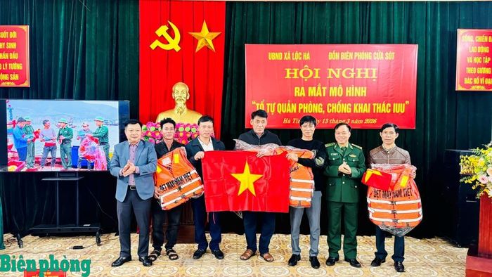 Đại diện Bộ đội Biên phòng tỉnh Hà Tĩnh và Ủy ban Nhân dân xã Lộc Hà trao tặng cờ Tổ quốc, phao cứu sinh, áo phao cho “Tổ tự quản phòng, chống khai thác IUU”. Ảnh: Thế Mạnh