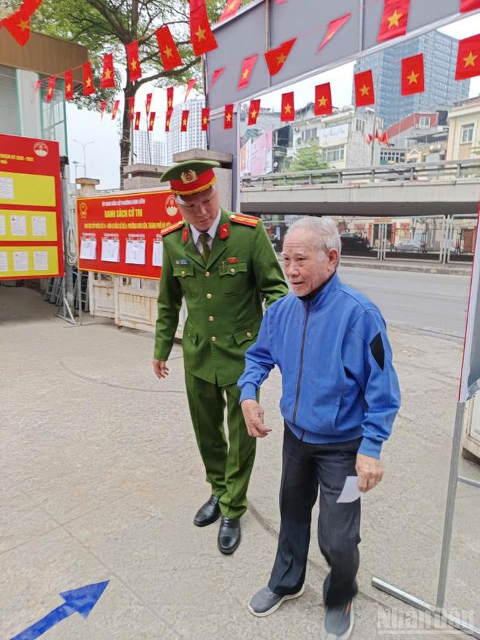 Hình ảnh người cao tuổi được dìu vào khu vực bỏ phiếu thể hiện tinh thần trách nhiệm, sự chu đáo của công tác tổ chức bầu cử.
