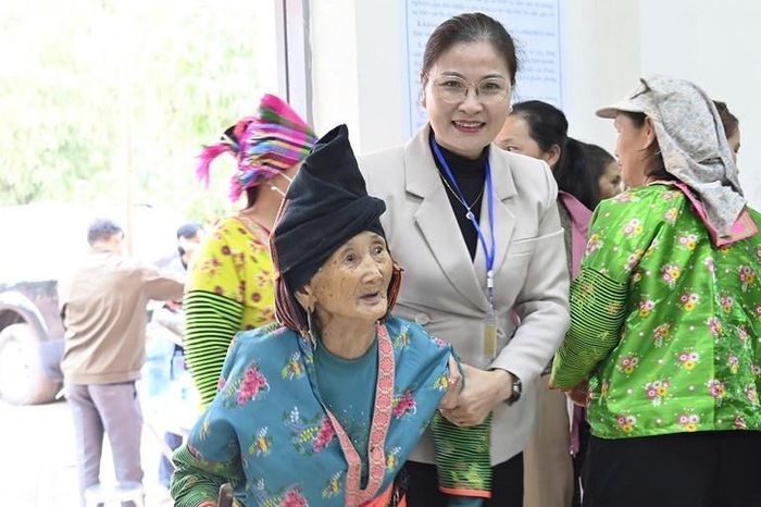 Cán bộ xã Mường Nhé đỡ cụ Trá Thị Dềnh trong khu vực bỏ phiếu.