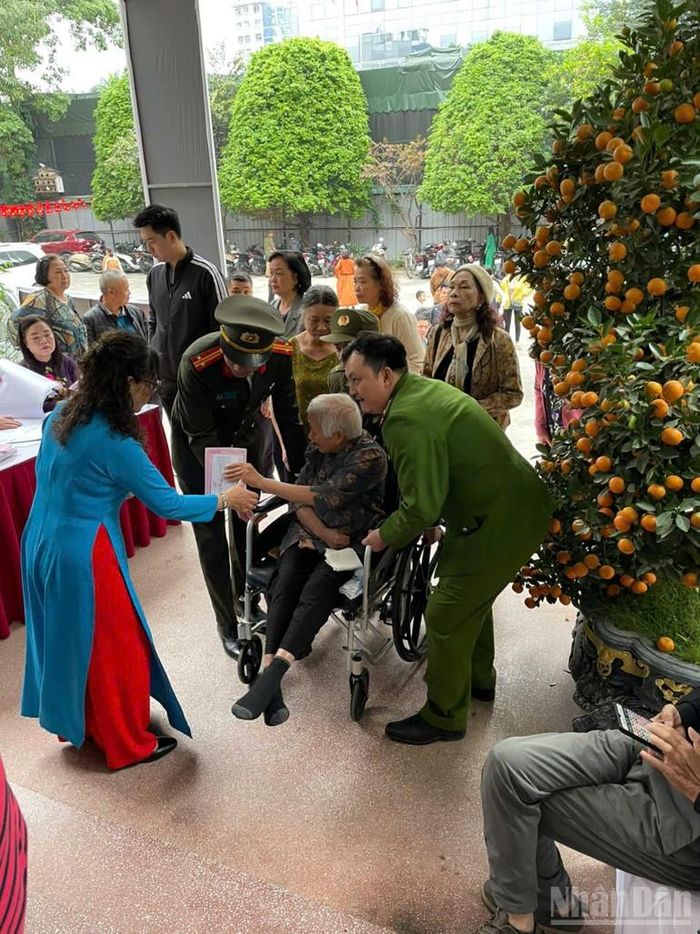 Tại khu vực bỏ phiếu, lực lượng tình nguyện viên nhẹ nhàng giúp đỡ người cao tuổi đang ngồi xe lăn vào phòng bầu cử, tạo nên hình ảnh ấm áp trong ngày hội của toàn dân.