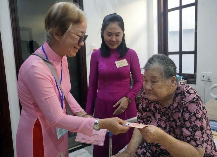 Nhân viên tổ bầu cử phát thẻ cử tri cho cụ bà Lê Thị Nghiệp, 89 tuổi.