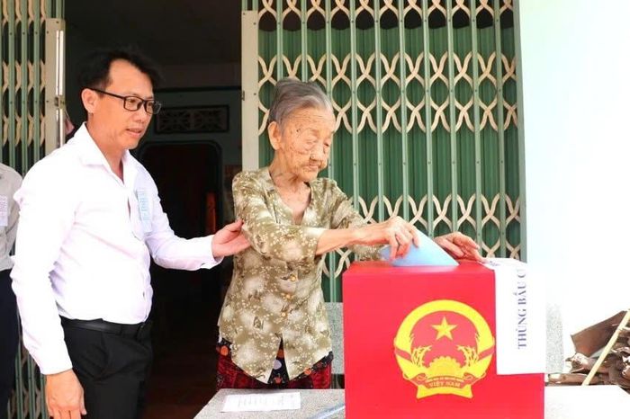 Tổ bầu cử lưu động đưa thùng phiếu đến nhà cử tri Hà Thị Riêu (90 tuổi, khu phố Phú Thuận)