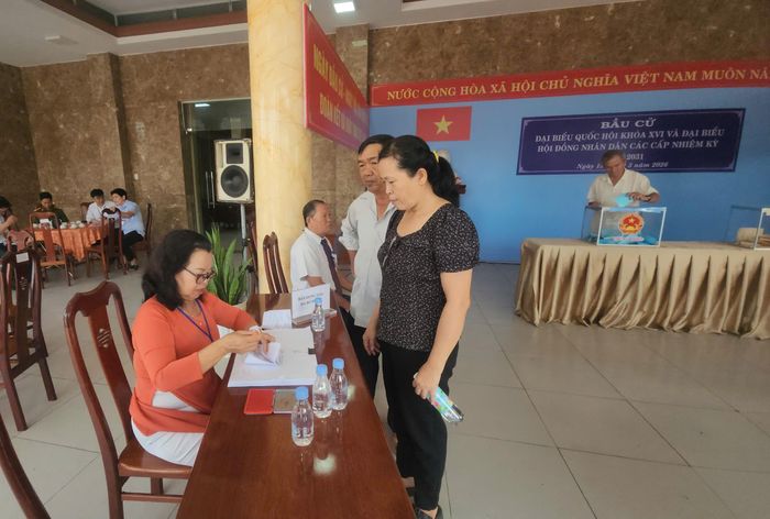 Cử tri chờ đóng dấu thẻ cử tri để hoàn thành việc bầu cử