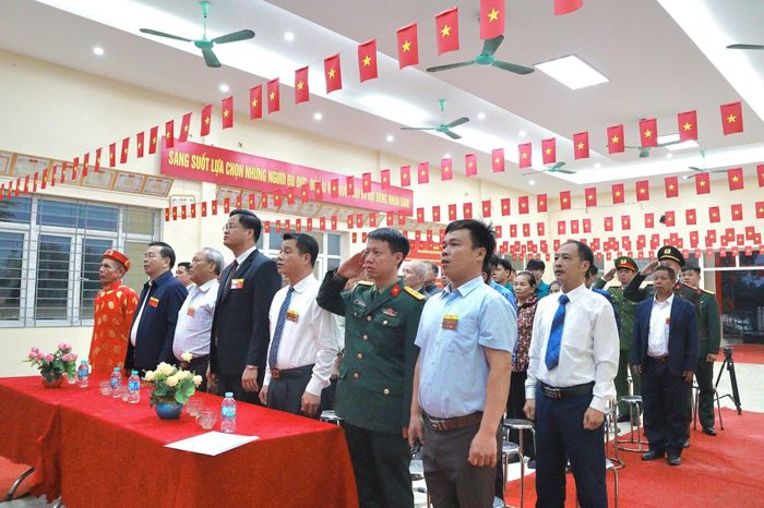 Các đại biểu và cử tri chào cờ tại Lễ khai mạc Khu vực bỏ phiếu số 57 (thôn Phú Đa) . Ảnh: Nguyễn Mai