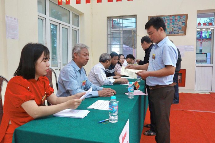Các cử tri làm thủ tục nhận phiếu bầu. Ảnh: Nguyễn Mai