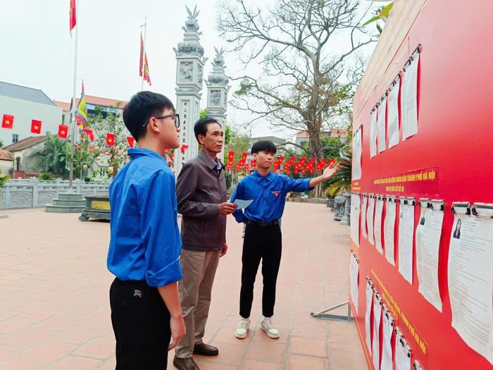 Cử tri được đội ngũ tình nguyện hướng dẫn khi tới điểm bầu cử tại Đình thôn Bạch Trữ. Ảnh PV