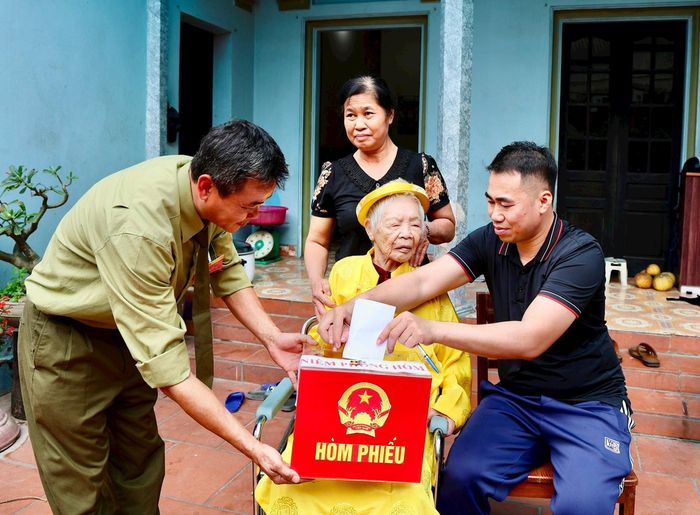 Cử tri Nguyễn Thị Bài, 96 tuổi được tổ bầu cử mang hòm phiếu phụ đến tận nhà để thực hiện quyền công dân. Ảnh: Ánh Ngọc 