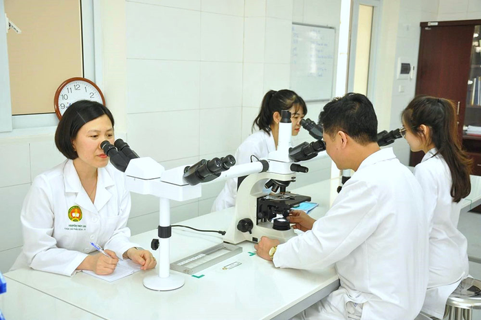 Trung tá, TS Nguyễn Thùy Linh (ngoài cùng, bên trái) tham gia hội chẩn tiêu bản ca bệnh khó trên kính hiển vi 5 đầu. 