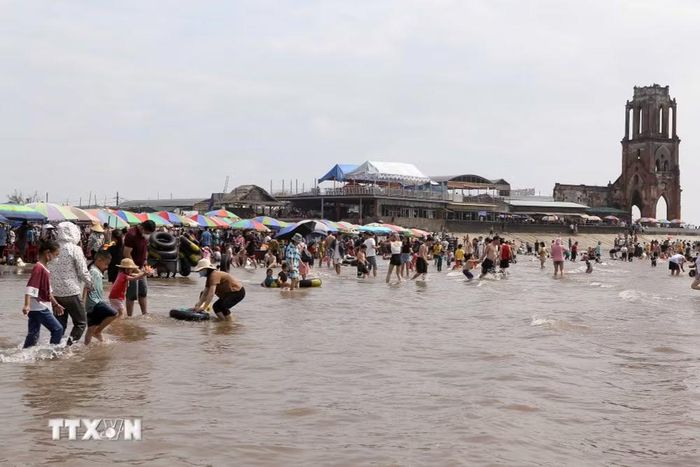 Đông đảo người dân và khách du lịch đến tắm biển tại khu vực nhà thờ đổ Hải Lý. (Ảnh: Công Luật/TTXVN)