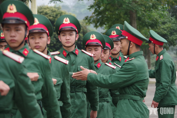 Đồng chí Tiểu đội trưởng trực tiếp uốn nắn động tác cho chiến sĩ mới trong giờ huấn luyện. 