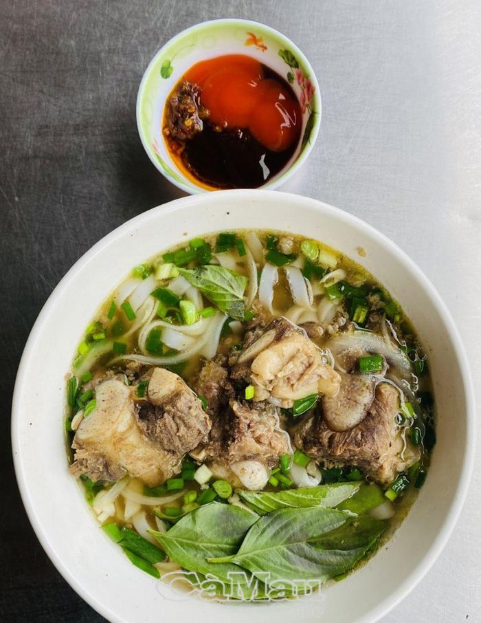 Phở xương bò đậm đà, ăn kèm tương, ớt và sa tế cay nồng.