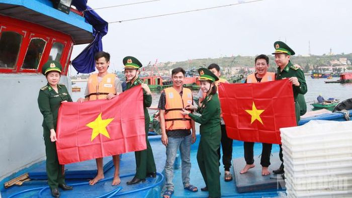 Cán bộ, chiến sĩ Bộ đội Biên phòng thành phố Hải Phòng tặng cờ Tổ quốc và áo phao cho ngư dân.