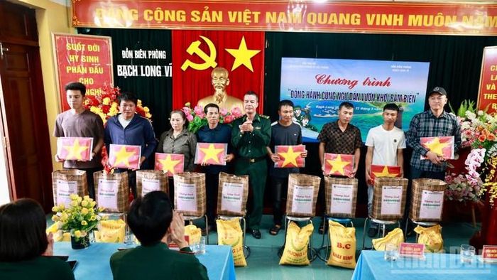 Trung tá Hoàng Nam, Đồn trưởng Đồn Biên phòng Bạch Long Vĩ trao quà và tặng cờ Tổ quốc cho hộ dân có hoàn cảnh khó khăn trên đảo.