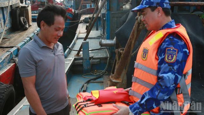 Thượng tá Nguyễn Ba Long tặng cờ Tổ quốc và áo phao cho ngư dân hoạt động tại vùng biển Bạch Long Vĩ.