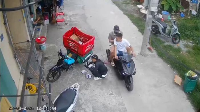  Thanh niên áo trắng đạp vào lưng shipper đang ngồi lựa hàng để giao cho khách. 