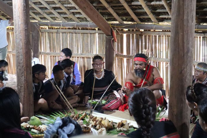 Già làng và các thành viên ban tế lễ cùng quây quần bên lễ vật, thực hiện nghi thức cầu an cho gia đình tại nhà dài. Ảnh: Trần Phương