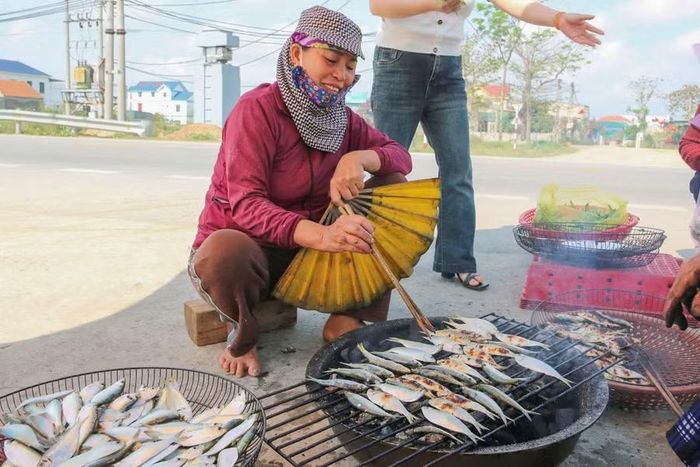 Dọc ven biển, có đến hàng chục phụ nữ ngồi nướng cá. Đôi tay vừa thoăn thoắt lật, quạt, miệng vừa liên tục chào mời khách dừng chân ghé quán thưởng thức cá trích.