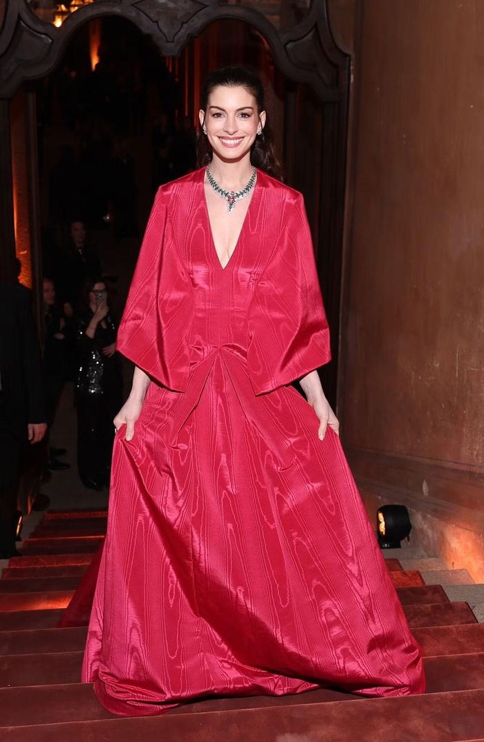 Anne Hathaway tham dự sự kiện với thiết kế Valentino Haute Couture bằng lụa moiré đỏ rực, phom dáng bồng bềnh. Bộ váy gợi nhớ đến trang phục mà Meryl Streep diện trong vai tổng biên tập Runway - Miranda Priestley - ở phần tiếp theo của bộ phim The Devil Wears Prada. Thiết kế của Hathaway gây ấn tượng với phần cổ khoét sâu làm tôn trọn bộ trang sức cỡ lớn, cùng chi tiết cape buông dài phía sau, tạo nên hiệu ứng chuyển động mềm mại và thanh lịch.
