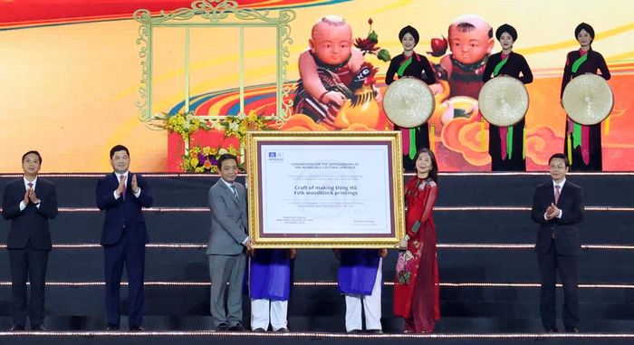  Bà Pauline Tamesis, Điều phối viên thường trú Liên Hợp quốc tại Việt Nam trao Bằng của UNESCO ghi danh Nghề làm tranh dân gian Đông Hồ vào Danh sách Di sản văn hóa phi vật thể cần bảo vệ khẩn cấp cho đại diện Việt Nam. 