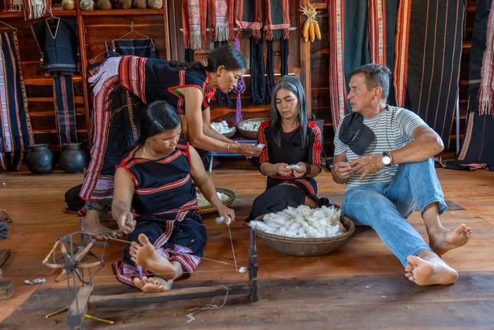  Du khách người Hà Lan tìm hiểu cách xe sợi từ cây bông trồng tự nhiên. Ảnh: Quốc Nguyễn 